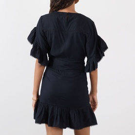 Model wearing Isabel Marant Etoile Melicia Ruffle Mini Dress in black with pompom trim, ruffled skirt and tie waist, back view