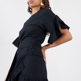 Model wearing Isabel Marant Etoile Melicia Ruffle Mini Dress in black with pompom trim, short sleeves, and ruffled skirt detail