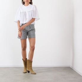 Model wearing Isabel Marant Etoile Eveja Striped Shorts in multi, styled with a white oversized top and tan cowboy boots.
