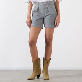 Model wearing Isabel Marant Etoile Eveja Striped Shorts in multi, mid-rise with rolled hems, styled with tan cowboy boots.