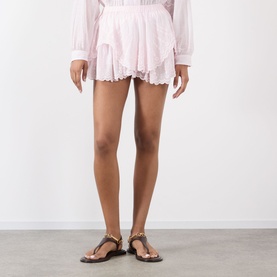 Model wearing Isabel Marant Etoile light pink cotton shorts with frill hem, styled with strappy embellished flat sandals.