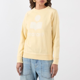 Model wearing Isabel Marant Etoile Millyny Logo Sweatshirt in light yellow with white logo print, styled with light blue jeans.
