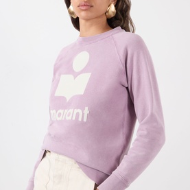 Model wearing Isabel Marant Etoile Millyny Logo Sweatshirt in rosewood with ecru logo print, round neck, raglan sleeves. Styled with cream trousers