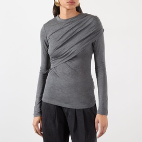 Model wearing Isabel Marant Etoile grey long-sleeve top with diagonal ruched draping across the front, styled with black wide-leg trousers.