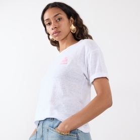 Model wearing Isabel Marant Etoile Koldia Logo T-Shirt in white with pink chest logo, short sleeves and turn-up cuffs, styled with light blue jeans.