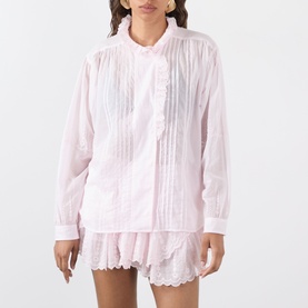 Model wearing Isabel Marant Etoile Leota Ruffle Blouse in light pink with front pleats and ruffled neckline, styled with matching shorts.