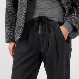 Model wearing Isabel Marant Etoile faded black cotton trousers with drawstring waist, styled with grey top and textured jacket.