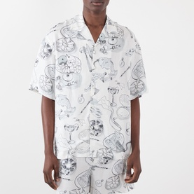 Model wearing Jacquemus Fish Graphic Bowling Shirt in off-white with all-over sketch print, notched collar, short sleeves, styled with matching