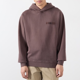 Model wearing Jacquemus brown cotton hoodie with tonal chest logo, styled with khaki trousers