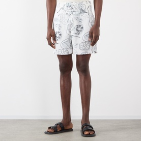 Model wearing Jacquemus Fish Graphic Shorts in off-white with navy print, elasticated waist. Styled with black leather sandals.