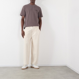 Model wearing Jacquemus brown cotton T-shirt with cream wide-leg trousers and white trainers