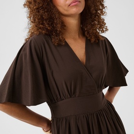 Model wearing Kaffe dress in Coffee Bean, featuring wrap-style V-neckline, flutter sleeves, and cinched waist detail.