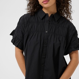 Model wearing Kaffe black deep short-sleeve shirt with ruched gathering detail across chest and ruffled sleeves