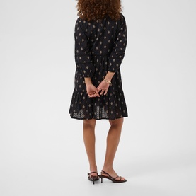 Model wearing Kaffe dress in Black Gray Vintage Baroq, rear view, with long sleeves, flared hem, and strappy heeled mules.