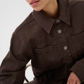Model wearing Kaffe Coffee Bean leather-look jacket with snap button fastening and chest pockets, styled with white bag strap detail.