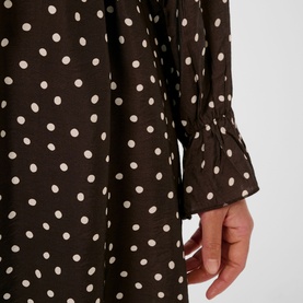 Dark brown and white polka dot dress with fluted cuff sleeve detail, close-up view
