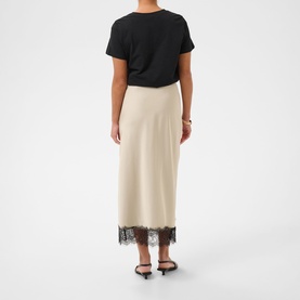 Model wearing Kaffe Feather Gray midi skirt with black lace hem trim, styled with a black T-shirt and black heeled mules.