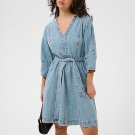 Model wearing light blue denim V-neck belted mini dress with three-quarter sleeves, styled with a small black shoulder bag