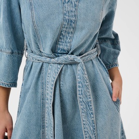 Model wearing light blue denim dress with tie waist belt, three-quarter sleeves, and vertical seam detailing