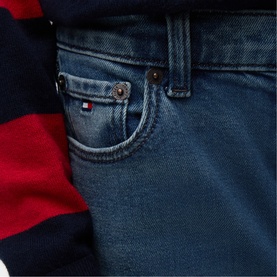 Tommy Hilfiger children's vintage medium stretch jeans close-up, showing logo flag patch on fifth pocket, styled with striped top