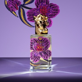 Sisley Eau du Soir Eau de Parfum bottle with gold lion cap, purple floral orchid design, on lavender background