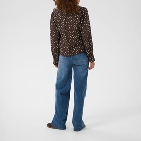 Model wearing Kaffe top in Coffee Bean Turtledove polka dot print, styled with blue wide-leg jeans, seen from behind.