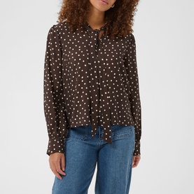 Model wearing Kaffe blouse in Coffee Bean Turtledove spot print, long sleeves, tie neck detail, styled with blue jeans