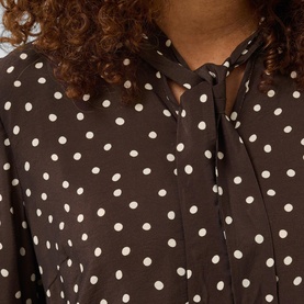 Model wearing Kaffe dress in Coffee Bean with cream polka dot print and tie-neck detail