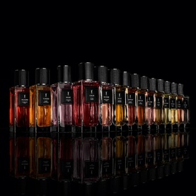 YSL Coeur Eau de Parfum displayed in a collection of richly toned glass bottles arranged in a row against a black background
