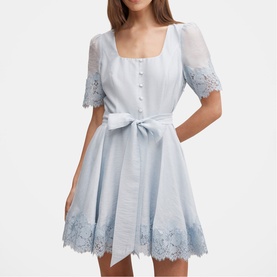 Model wearing pale blue mini dress with square neckline, lace trim sleeves and hem, button front, and tied waist bow