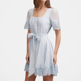 Model wearing pale blue short-sleeve mini dress with lace trim hem and sleeves, button-front bodice and self-tie waist belt