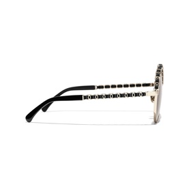 Gold and black oversized sunglasses shown from the side, with embellished temples featuring repeating logo detail and black tips.