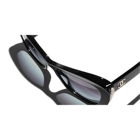 Chanel sunglasses in black with silver CC logo detail on temple, close-up showing gradient grey lenses and glossy frame