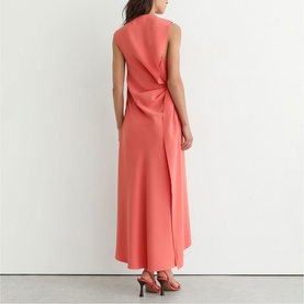 Model wearing Reiss coral pink sleeveless maxi dress with draped open back detail, styled with coral heeled sandals.