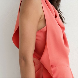 Model wearing Reiss coral pink dress, close-up detail showing draped neckline and sleeveless silhouette