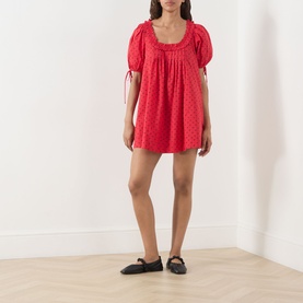 Model wearing Damson Madder Jemima Cherry Mini Dress in Red Cherries; broderie-style cotton with puff sleeves, scoop neck, and pleated skirt. Styled