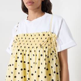 Model wearing Damson Madder Butter Spot cotton dress with shirred bodice and tie straps, styled over a white T-shirt