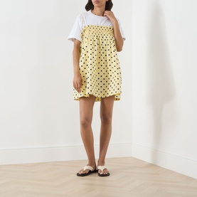 Model wearing Damson Madder Butter Spot Dress in yellow polka dot cotton, styled with white tee underneath and flat sandals.