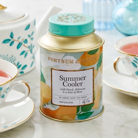 Fortnum & Mason Summer Cooler Silky Tea Bag Tin, gold with teal lid and peach fruit print, styled with teacups and teapot