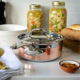 Hestan Copperbond Saucepan 18cm with glass lid, copper exterior and stainless steel handles, styled on marble surface with preserving jars and bread.