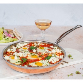 Hestan Copperbond Skillet 28cm in copper, shown with shakshuka and feta, styled alongside flatbread, salad and a glass of wine.