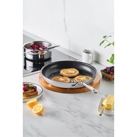 Hestan ProBond Luxe Non Stick Skillet 28cm in stainless steel, shown on bamboo board with pancakes, styled with saucepan and fresh fruit