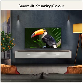 LG 43 Inch QNED7E Mini LED 4K Smart TV in black, wall-mounted in living room displaying vibrant toucan image, with text "Smart 4K. Stunning Colour