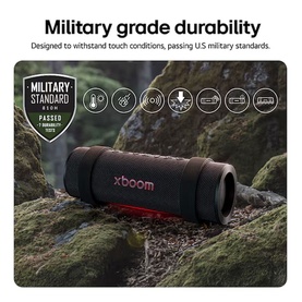 LG xboom Grab by will.i.am Bluetooth Speaker in black, shown outdoors on moss, with Military Standard durability icons