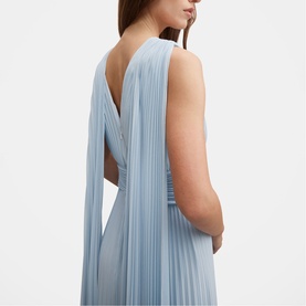 Model wearing pale blue sleeveless pleated maxi dress with crossover open back and long trailing panel detail