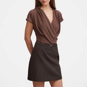 Model wearing brown wrap-style short sleeve top with V-neckline, styled with a dark brown belted mini skirt