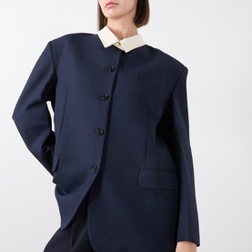 Model wearing navy blue structured jacket with black buttons and contrast cream collar, styled with matching shirt
