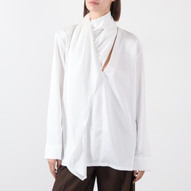 Model wearing white long-sleeve shirt with draped scarf neckline and keyhole cut-out detail, styled with dark trousers