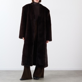 Model wearing Source Unknown Dhanila Faux Fur Coat in brown, longline with shawl collar, styled with dark wide-leg trousers