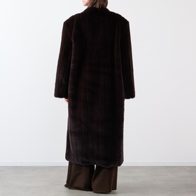 Model wearing Source Unknown Dhanila Faux Fur Coat in brown, longline faux fur with structured shoulders, paired with wide-leg trousers.